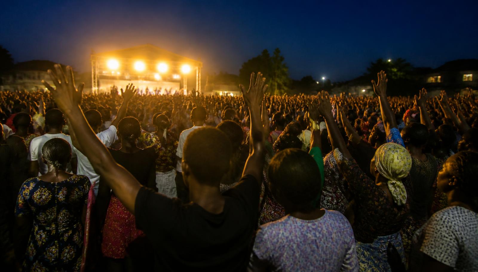 Worshippers with raised hands at an evening church gathering